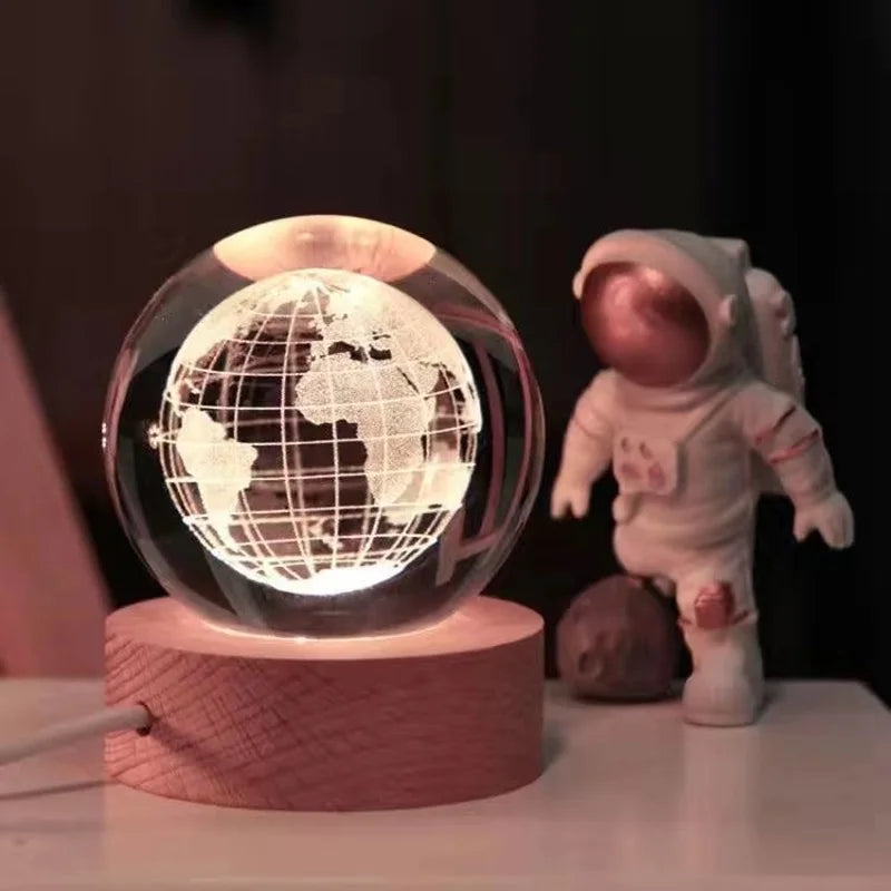 A 3D crystal ball night light with a glowing Earth sphere sits on a wooden base.