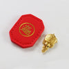 A red felt tag with a gold circular emblem and a small golden tortoise figurine.
