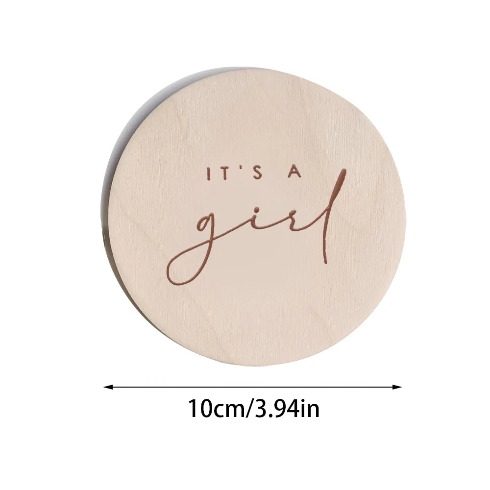 A round, light wood plaque with the cursive word girl engraved on it.