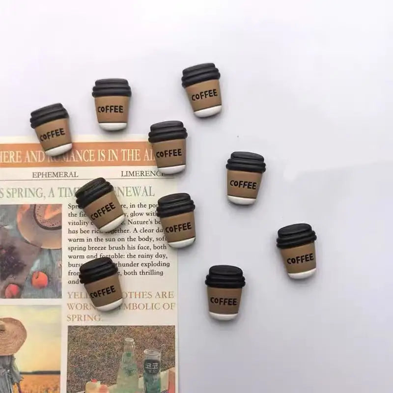 A collection of black coffee bean fridge magnets arranged on a white background.