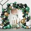 An elegant balloon garland arch featuring black, gold, and green balloons with greenery accents.