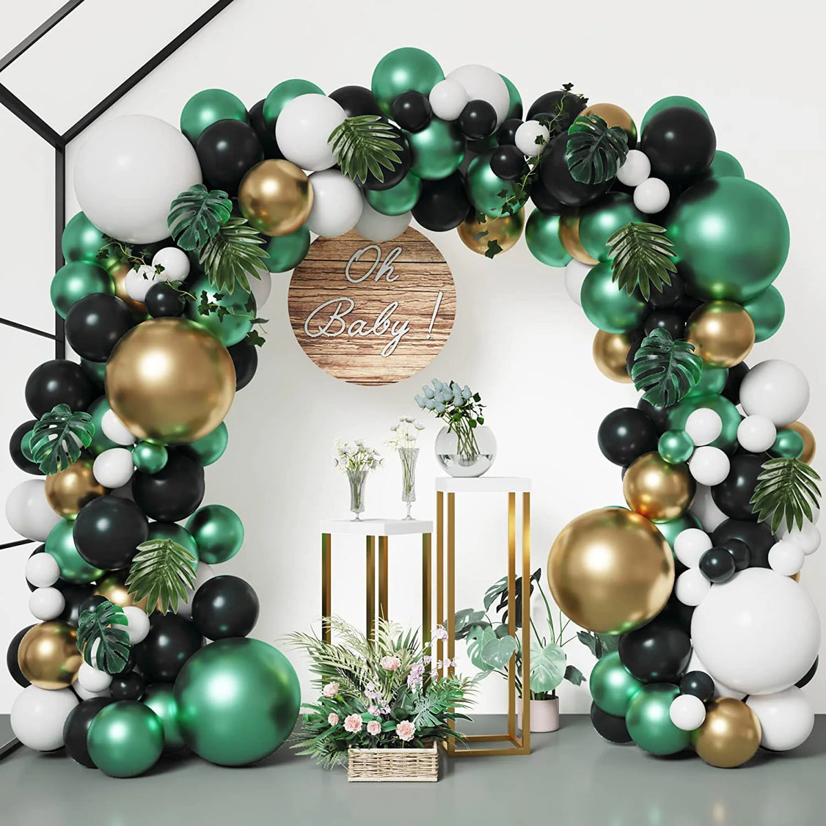 An elegant balloon garland arch featuring black, gold, and green balloons with greenery accents.