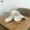 Jarrón decorativo moderno curvo impreso en 3D blanco sobre una mesa de madera.