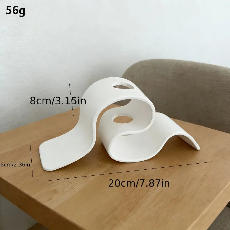 Jarrón decorativo moderno curvo impreso en 3D blanco sobre una mesa de madera.