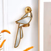 Gold resin animal wall hanging decor shaped like a bird mounted on a white wall.