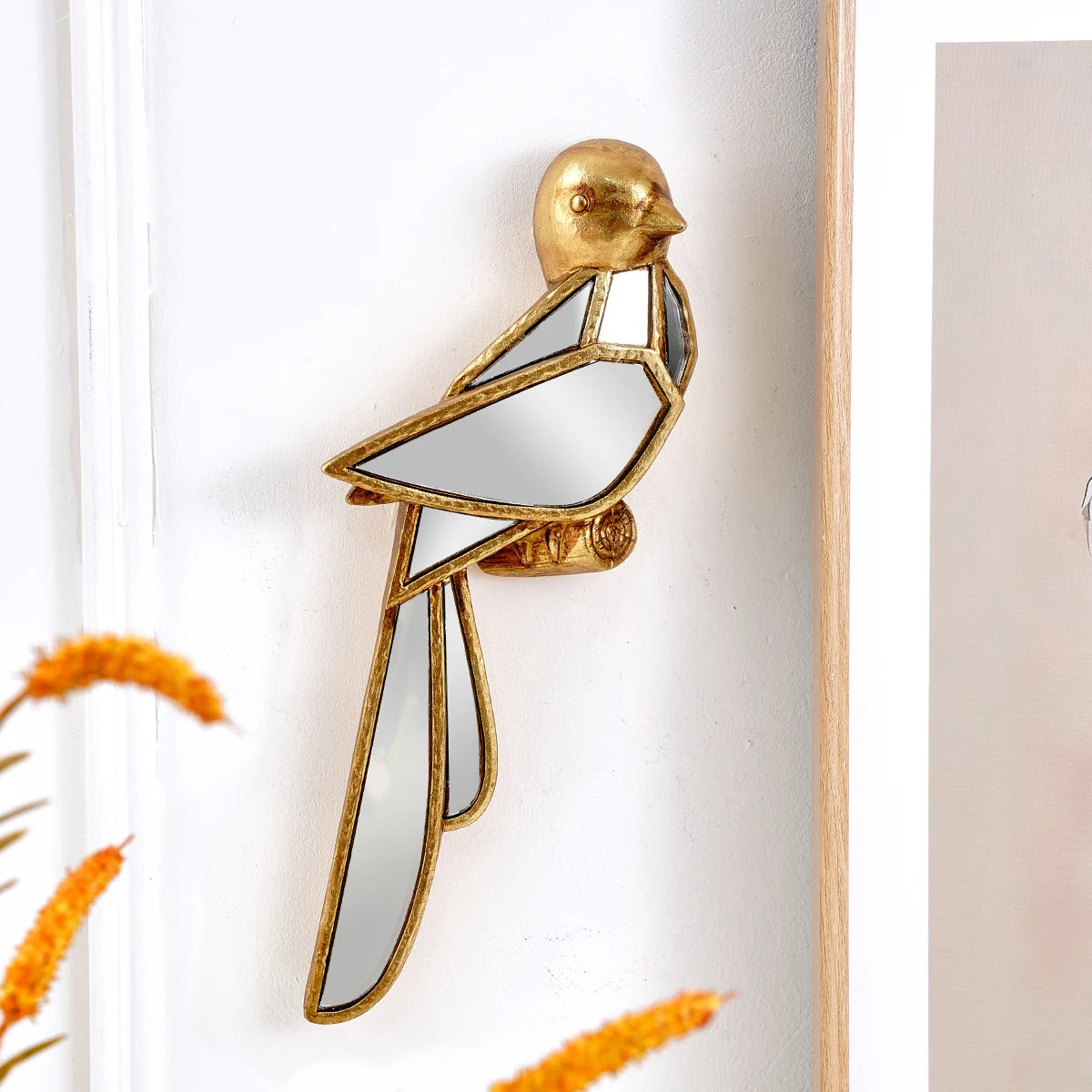Gold resin animal wall hanging decor shaped like a bird mounted on a white wall.