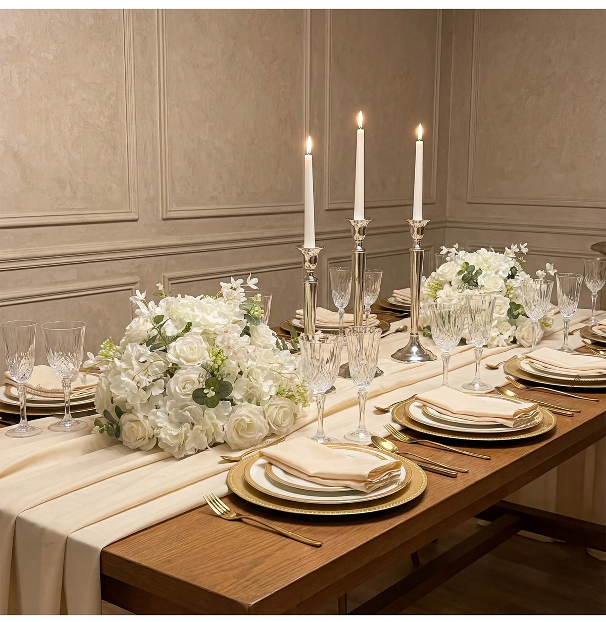 A table setting featuring a silk champagne rose and hydrangea flower ball centerpiece with tall candles.