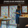 A woman stands in front of a window covered with stained glass film featuring colorful rainbow blocks, illuminating an interi