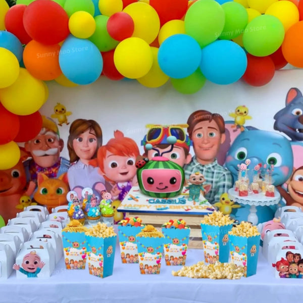 A colorful party supplies kit featuring balloons, tableware, and yellow corn snacks for a children's celebration.