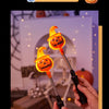 Une main tient une lanterne de citrouille orange sculptée et lumineuse contre un arrière-plan flou.