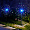 Deux feux d'artifice LED solaires verticaux, avec des traînées lumineuses bleues et vertes dans un jardin.