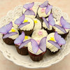 A plate of cupcakes decorated with purple butterfly toppers and white frosting.