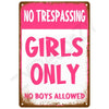 A pink vintage tin sign with white text that reads NO TRESPASSING GIRLS ONLY NO BOYS ALLOWED