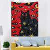 A tapestry wall hanging featuring a black cat with glowing yellow eyes against a red background.