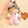 Un ours en peluche rose et duveteux portant des lunettes de pilote est attaché à une clé USB avec des sangles en cuir rose et