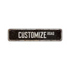 A dark rectangular aluminum street sign with the words CUSTOMIZE ROAD engraved on it.