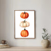 Wall art featuring three watercolor pumpkins in orange and cream tones framed in wood