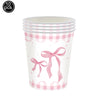 A clear plastic cup with a pink gingham pattern and a pink bow design for birthday party supplies.
