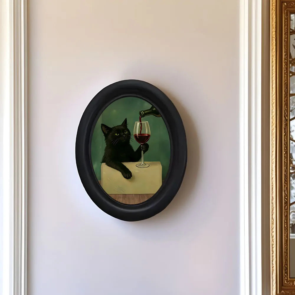 Framed wall art depicting a black cat drinking wine on a table.