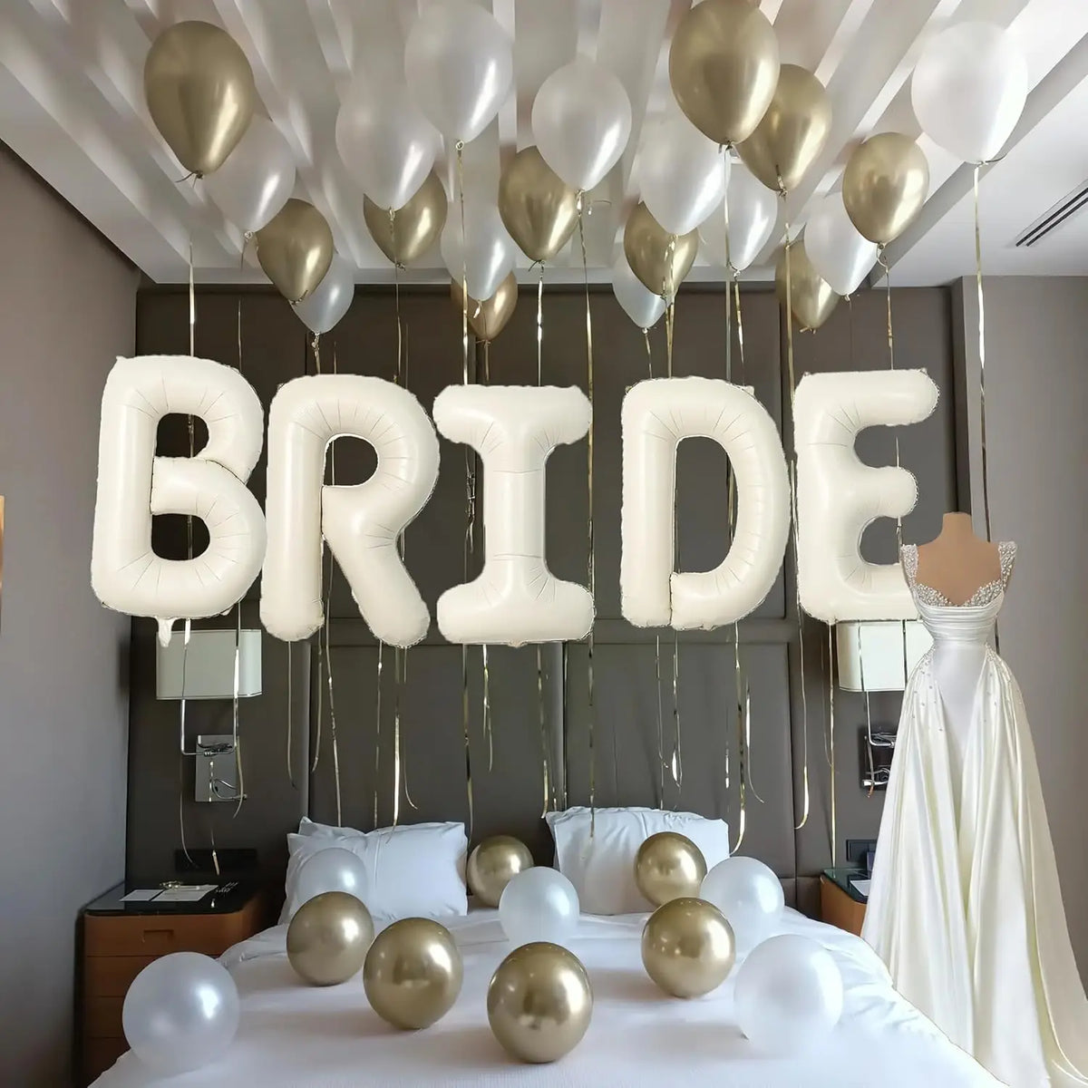 Elegant white and gold balloons spelling the word BRIDE above a bridal gown on a bed.