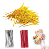 A pile of gold wire ties next to clear cellophane treat bags with colorful swirl candies.