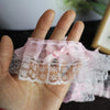 Pink lace trim with a delicate bow ruffle is held in a hand.