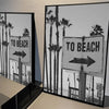 Black and white poster featuring a sign that reads To Beach with palm trees in the background