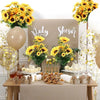A table display featuring an artificial sunflower bouquet, balloons, and treats for a baby shower event.