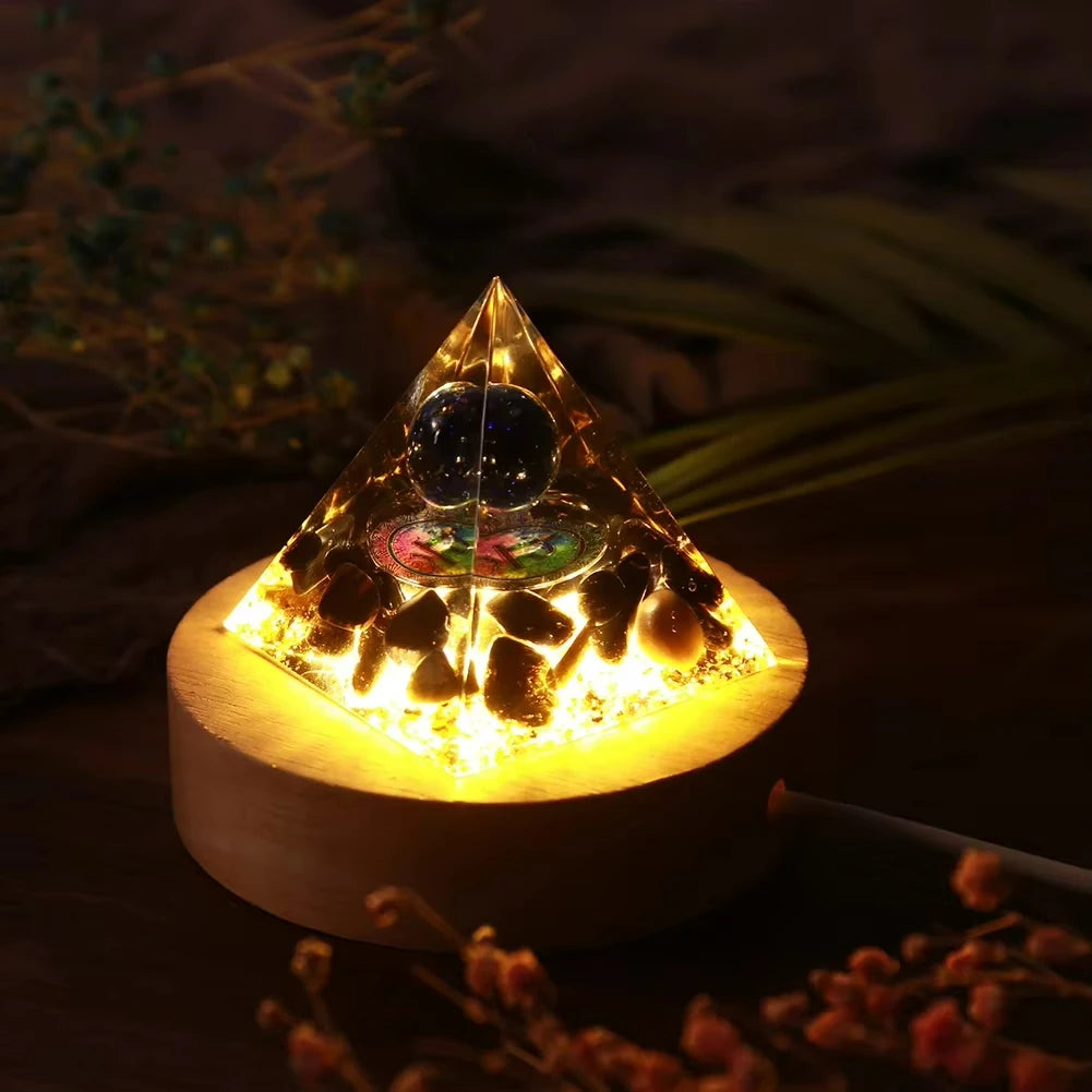 Handmade resin orgonite pyramid with natural obsidian and copper coil glowing brightly