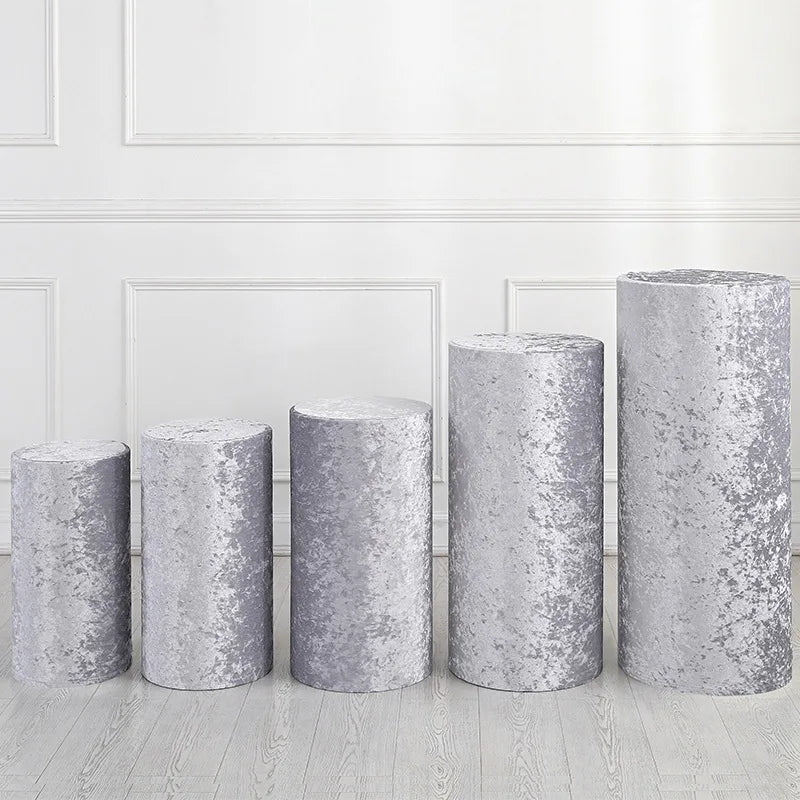 A row of four silver gray spandex cylinder stands used for event decor