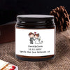 A dark glass jar candle with a label featuring the names Daniel & Canla and the date 12.12.2025
