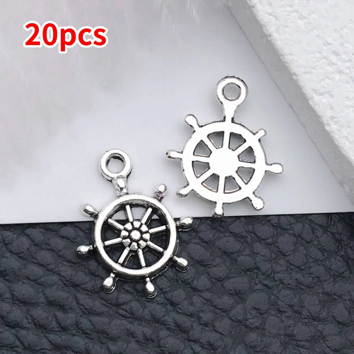 Silver vintage ship anchor charms for jewelry making displayed on black leather