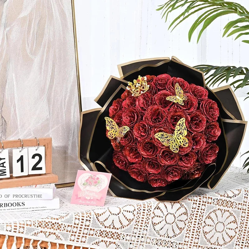 A bouquet of deep red glitter artificial roses displayed in a black decorative bowl on a white surface.