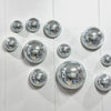 A collection of silver disco balls arranged on a white wooden surface.