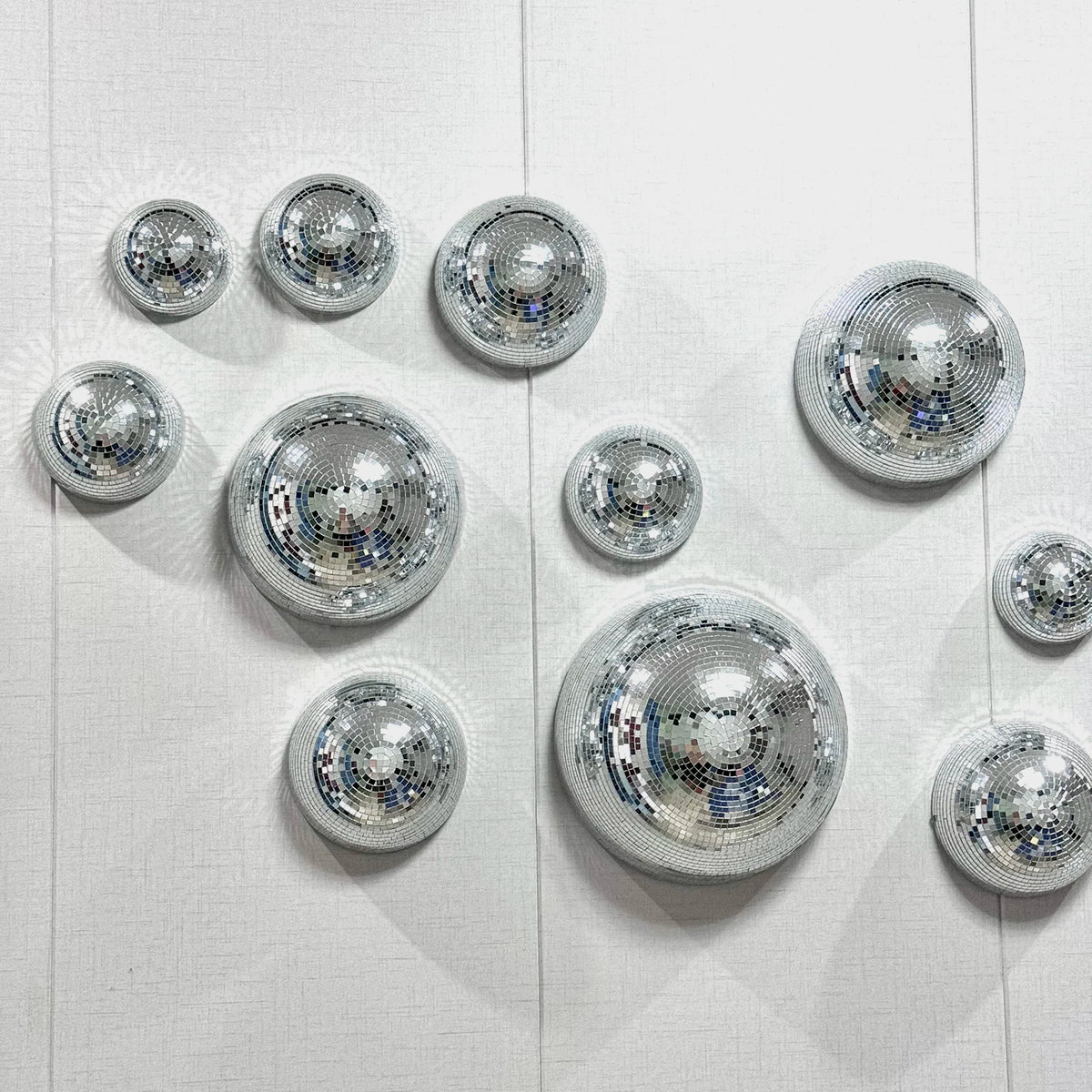 A collection of silver disco balls arranged on a white wooden surface.