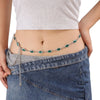 A woman wearing a green crystal waist chain over a denim skirt.