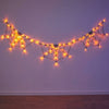 String lights shaped like spider webs illuminate a purple wall for Halloween decor.