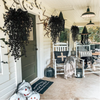 Artificial black vine hanging plants displayed on a porch with white furniture and decor.