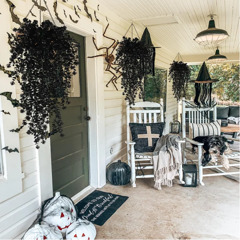 Artificial black vine hanging plants displayed on a porch with white furniture and decor.