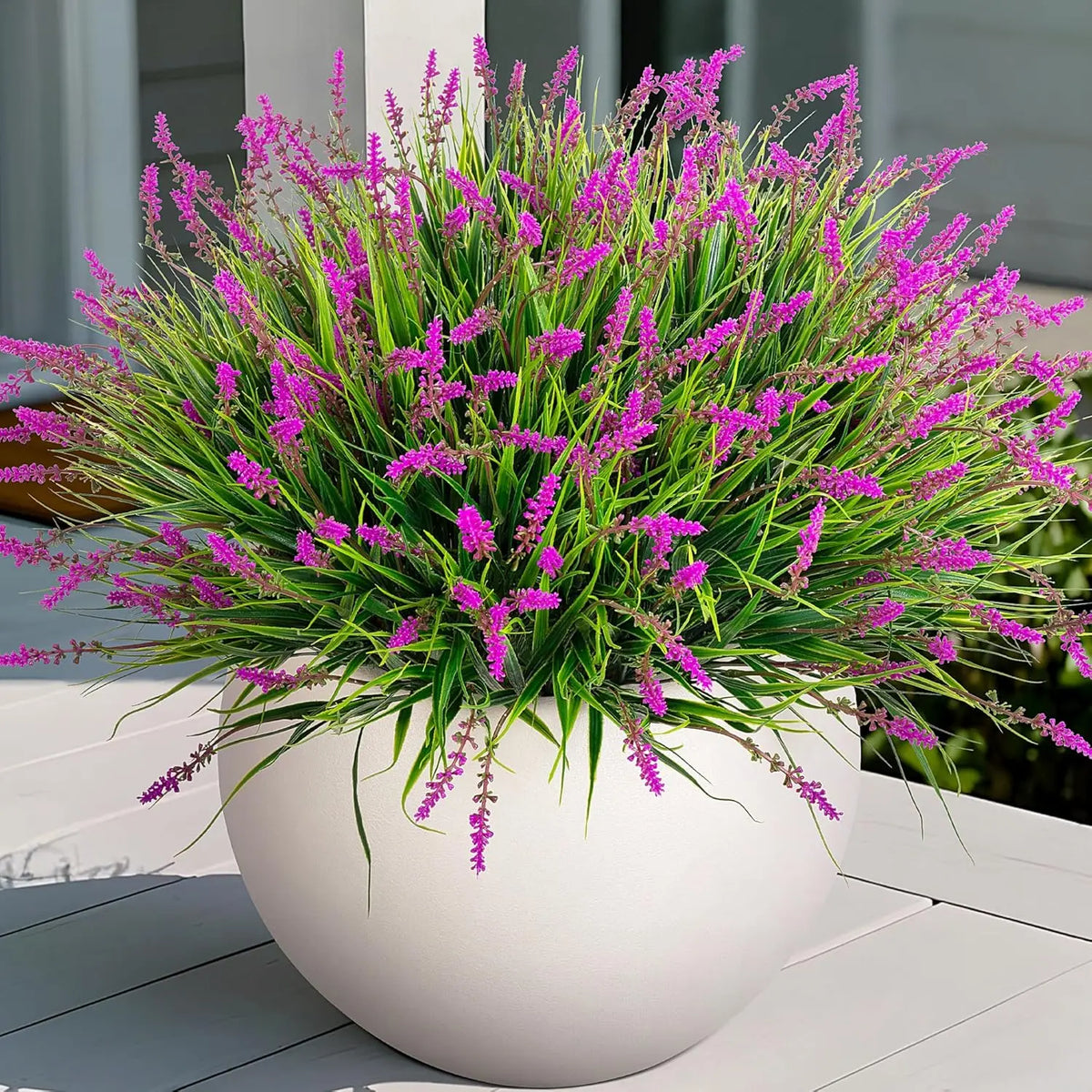 A potted artificial lavender plant with vibrant purple flowers in a white ceramic pot