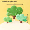 Green flower-shaped tree cake topper with leaves and trunk on a white cake.