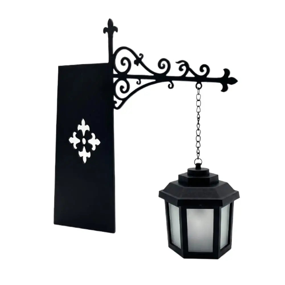 Black wrought iron lamp with a decorative scrollwork arm and a glass lantern shade