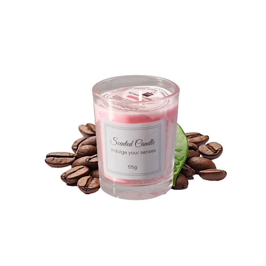 A glass jar of pink scented candle with a white label and loose coffee beans surrounding it.