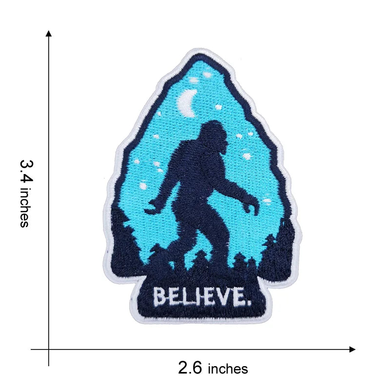 Blue embroidered patch featuring a silhouette of Bigfoot against a night sky with a crescent moon and the word BELIEVE.