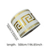 Roll of self-adhesive PVC baseboard trim featuring a gold and white brick pattern