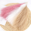 Ramo de pampas artificial con plumajes rosa y blanco, presentado en una estera tejida.