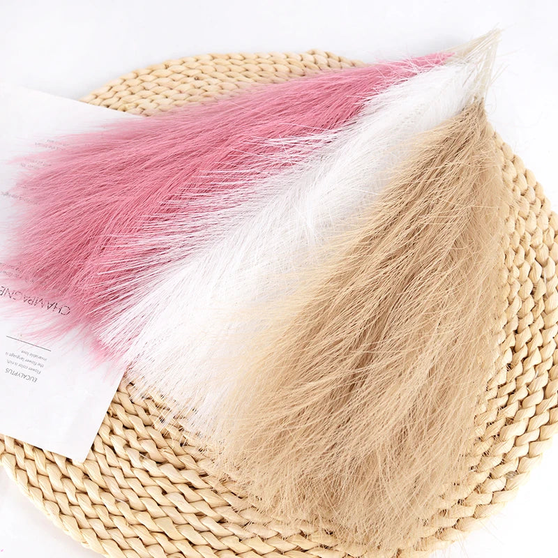 Ramo de pampas artificial con plumajes rosa y blanco, presentado en una estera tejida.