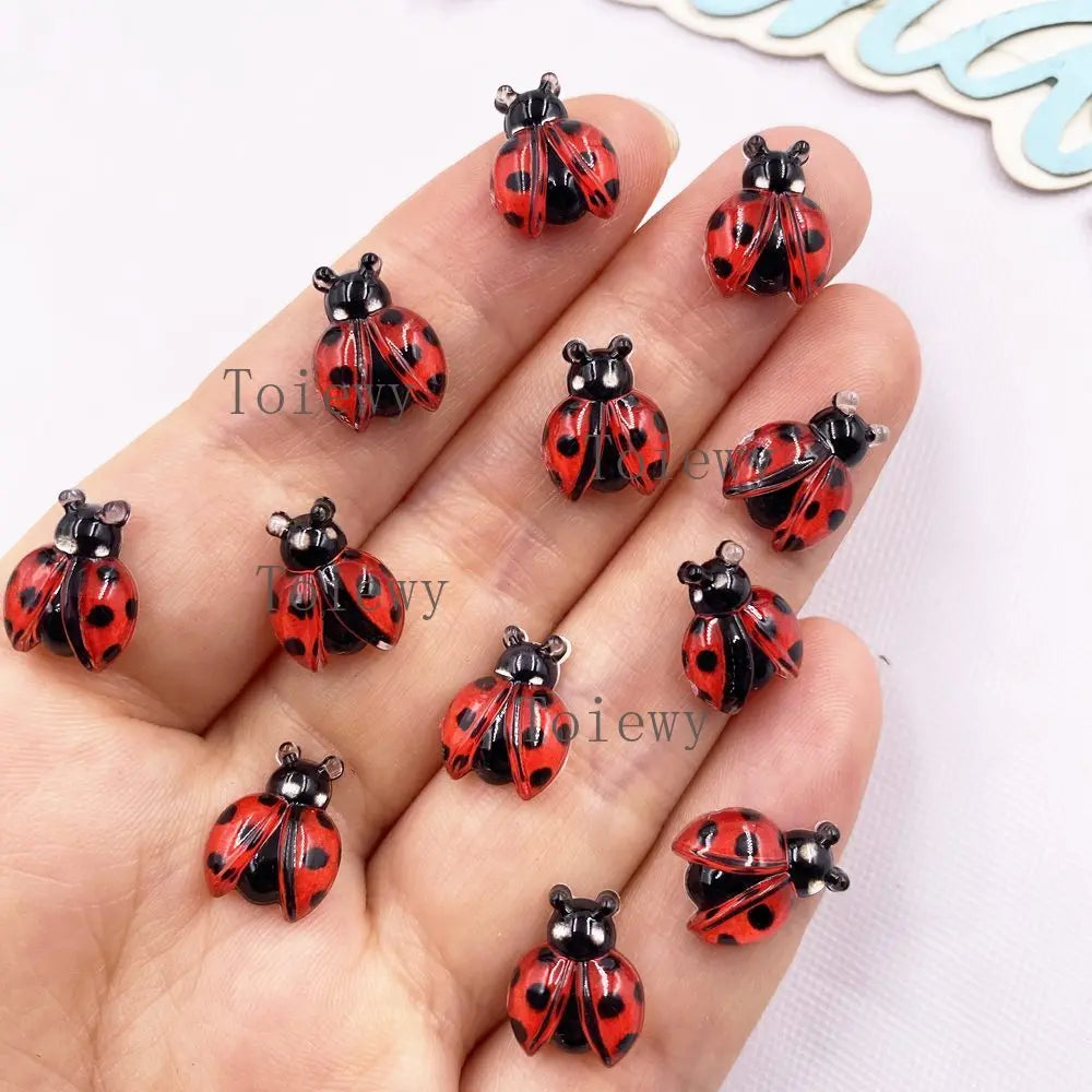 A hand displays several colorful resin beetle rhinestone appliques for DIY crafts.