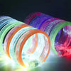 A close-up shot of ten glowing LED flash bracelets in various colors, including green, orange, and purple.