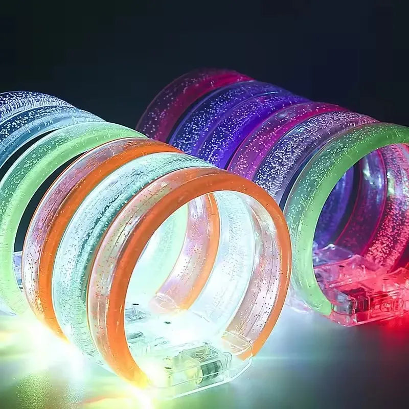 A close-up shot of ten glowing LED flash bracelets in various colors, including green, orange, and purple.